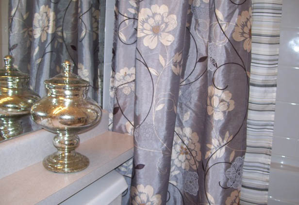 bathroom countertop accessorized with only 1 item with some sheen to it that matches the sheen on the shower curtain