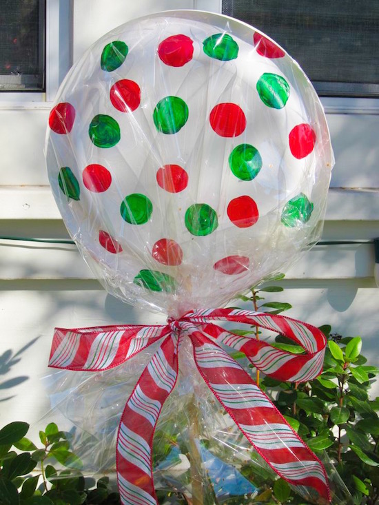 DIY dollar store lollipops for Christmas decor! Use paper plates (glued/stapled together) Christmas colored markers or paint, and cellophane. Stake them into the ground with a stick and tie off with ribbon.